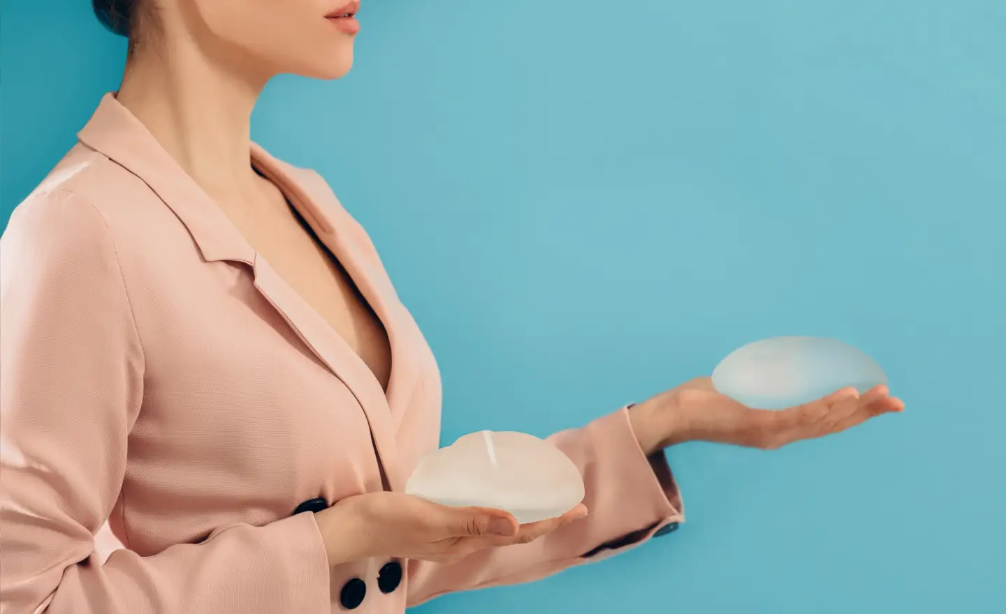 Woman comparing teardrop anatomical and round silicone breast implants side by side